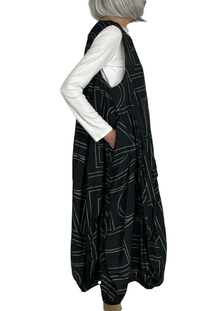side view of model wearing the Black Sleeveless Geometric Dress by Moyuru with a white tee underneath
