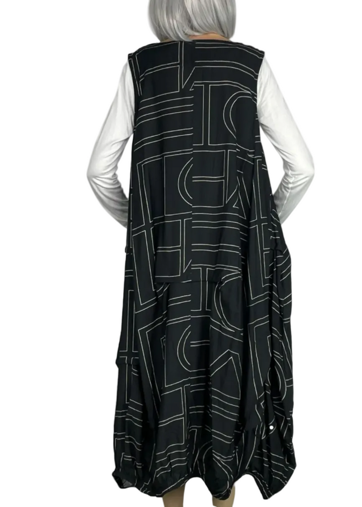 back view of model wearing the Black Sleeveless Geometric Dress by Moyuru with a white tee underneath 
