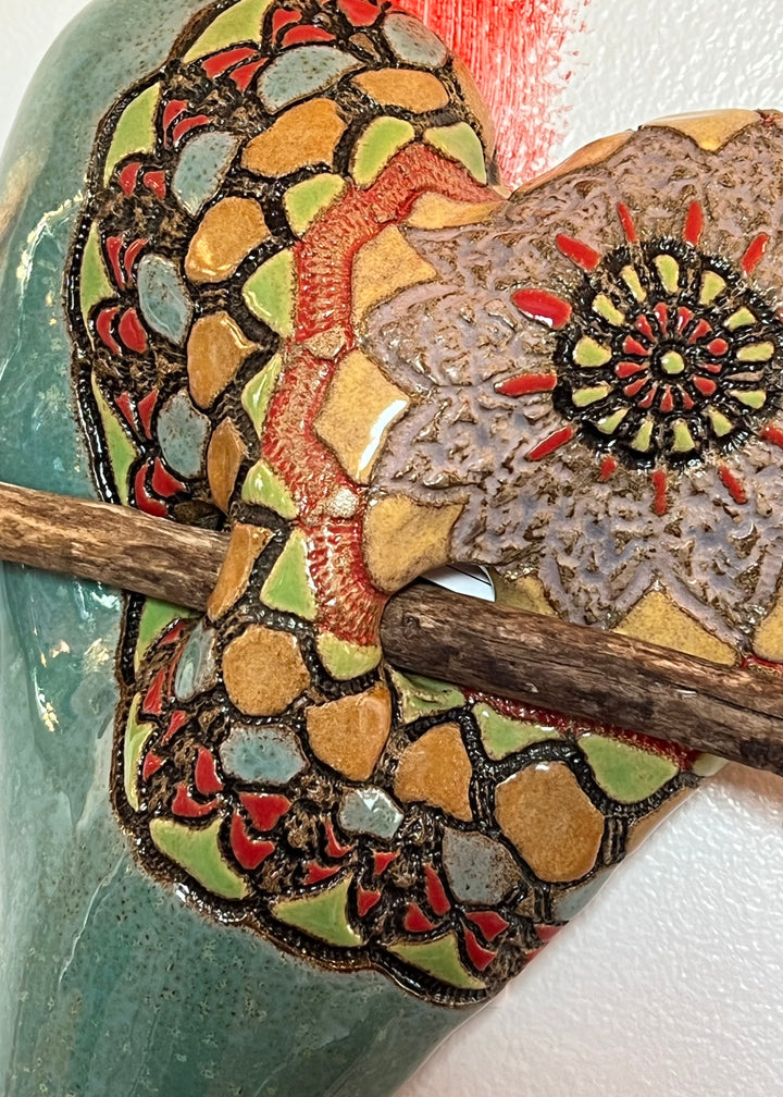 Close up view of The Adventures of Ali by Laurie Pollpeter Eskenazi Ceramic Heart Wall Sculpture