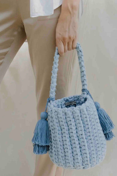 model carrying a Sky Blue colored Amalfi Bucket Bag with Tassels by Binge Knitting 