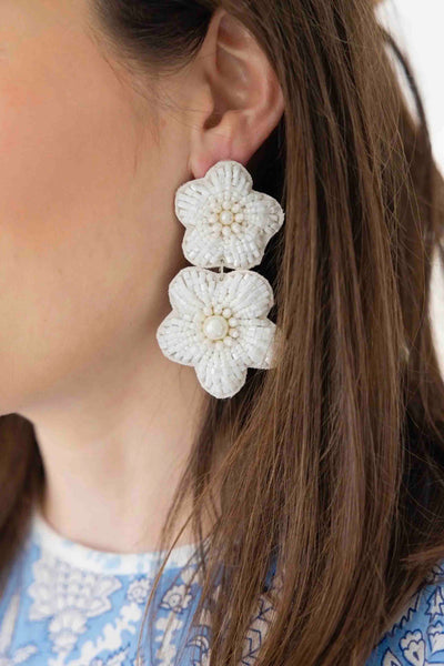 a model wearing the White Bali Double Flower Dangle Earrings by Beth Ladd Collections
