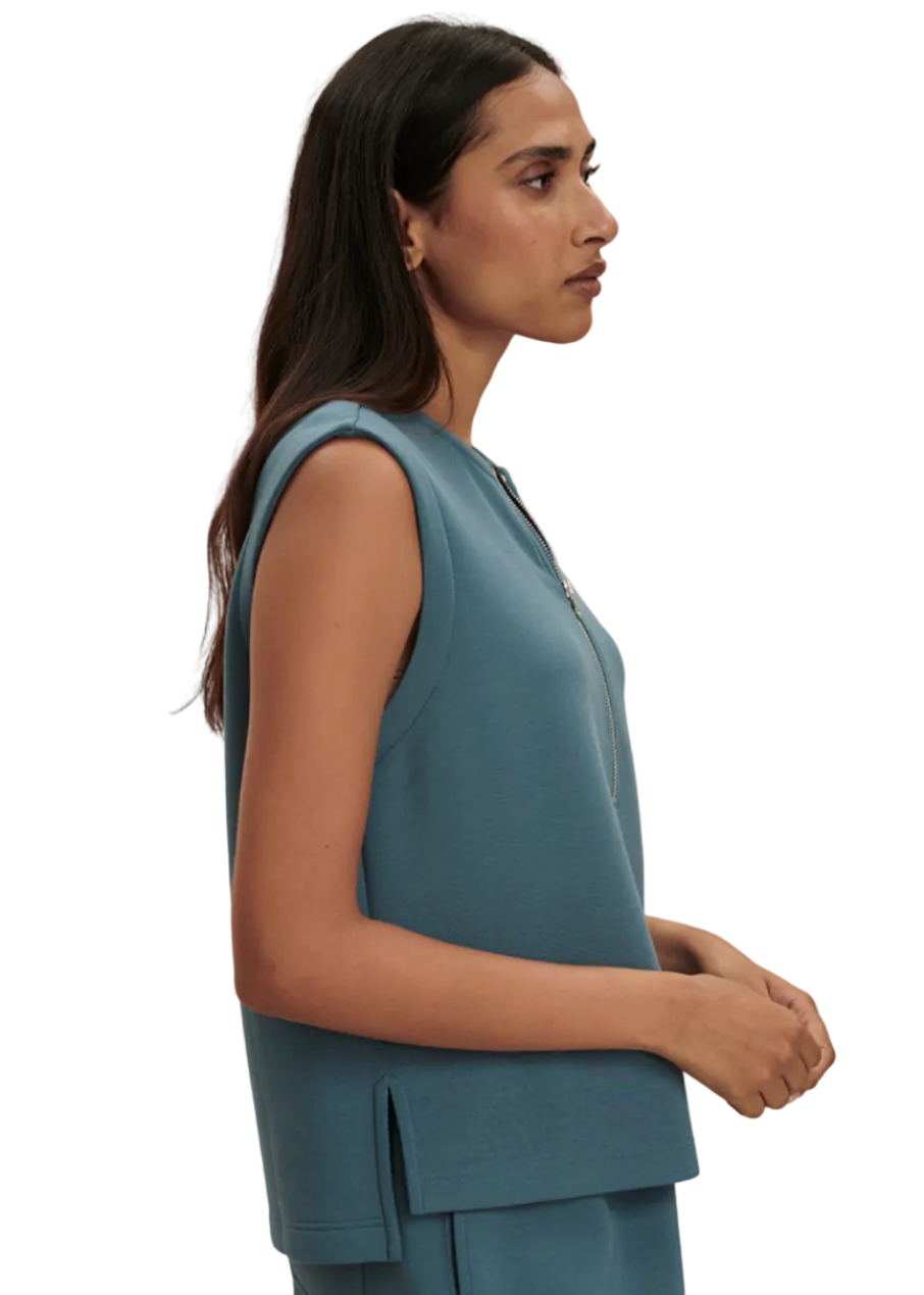 side view of model wearing the Simmons Half Zip Tank by Varley in Mallard Blue