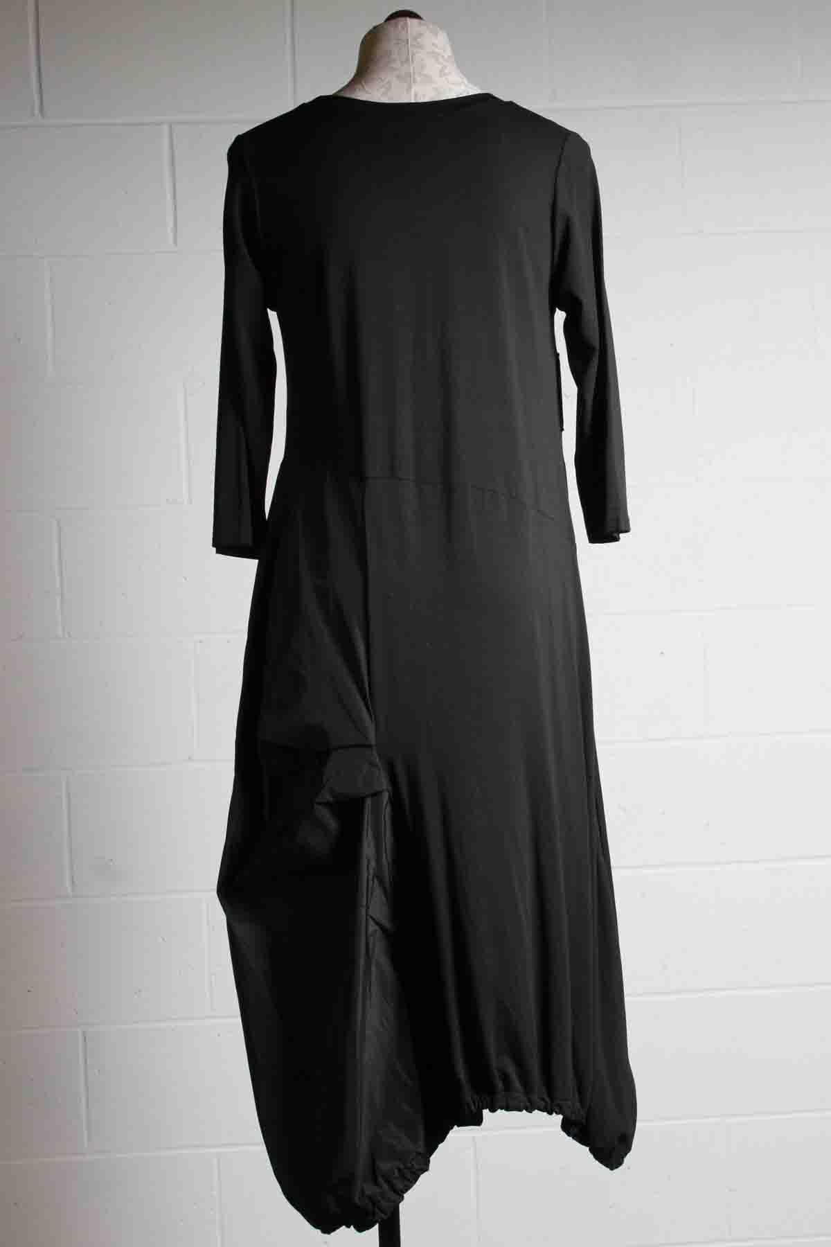 back view of black long sleeve dress by Reina Lee with an asymmetrical gathered bottom in contrasting fabrics