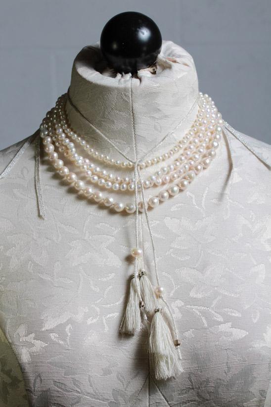 loosely tied adjustable white pearl 4 strand necklace from a choker length down by sliding a pearl down the silver metallic tasseled cords