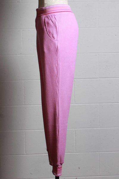 side view of magenta ribbed thermal pant with a multi colored striped elastic waistband and ankle bands