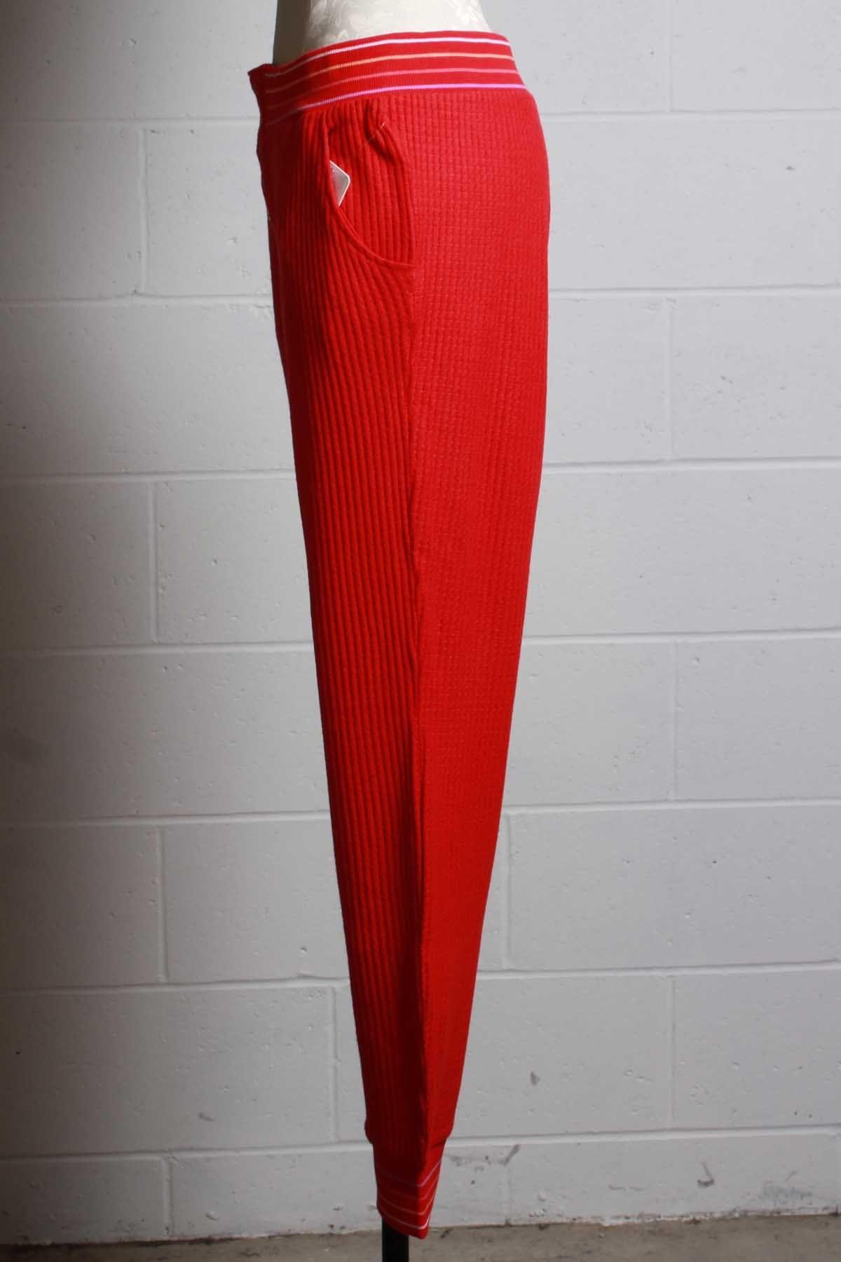 side view of red ribbed thermal pant with a multi colored striped elastic waistband and ankle bands