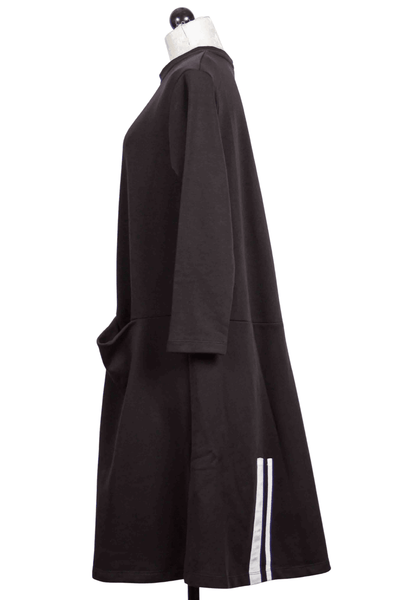 side view of black Long Sleeve Knit Dress by Alembika with Slouch Front Pockets with stripe detail on bottom side