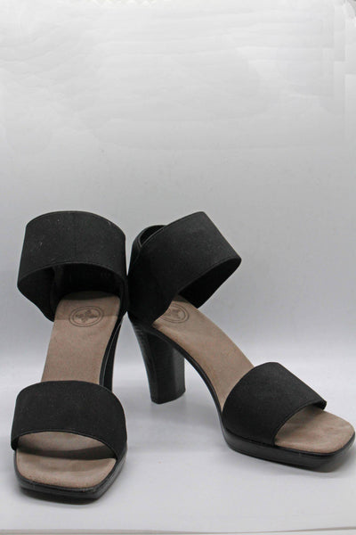 angled view of black cocktail sandal by Charleston Shoes with a 3 1/2" heel and a wide stretch upper toe band and ankle straps with a closed back