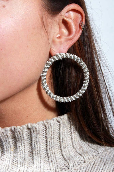 close up of 2 in circular post earring with silver and white beads wrapped around the hoop